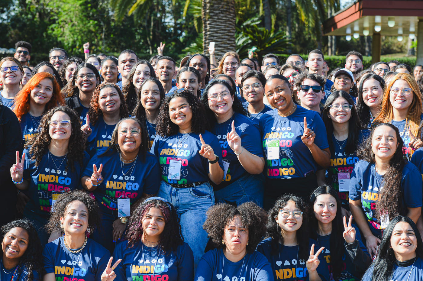 Jovens reunidos ao ar livre, sorrindo e celebrando a amizade com camisetas coloridas do projeto INDIGO.